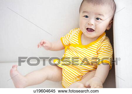 Stock Photography - Baby sitting on couch. Fotosearch