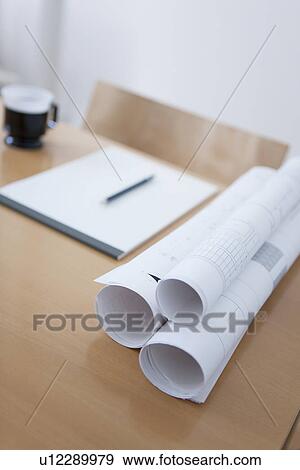 Stock Photo - Blueprints and coffee cup on vacant desk. Fotosearch