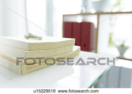 Books stacked on table near bookshelf View Large Photo Image Stock Photo - Books stacked on table near bookshelf. Fotosearch