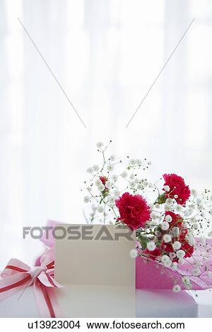Picture - Bouquet of carnations and baby's breath with a present and a card. Fotosearch