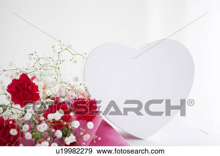 Stock Photo - Bouquet of carnations and baby's breath with a heart shaped gift box. Fotosearch