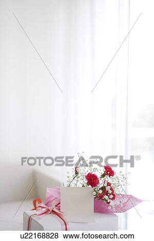 Stock Photo - Bouquet of carnations and baby's breath with a present and a card. Fotosearch