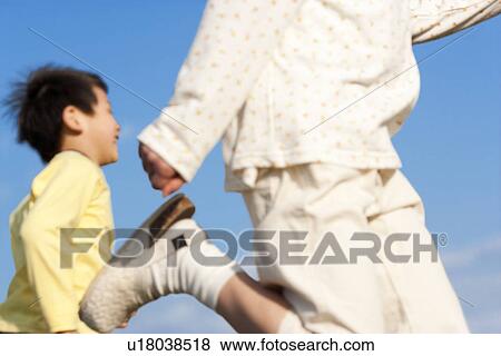 Stock Photo - Brother and sister running against a blue sky. Fotosearch