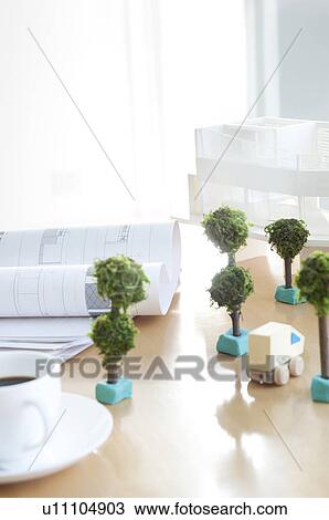 Stock Image - Building model and plans with model trees and coffee cup. Fotosearch
