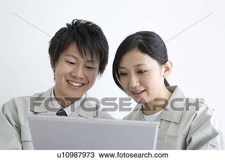 Stock Image - Business colleagues having conversation and looking at laptop. Fotosearch