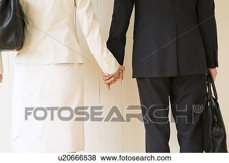 Stock Photo - Businessman and businesswoman holding hands. Fotosearch