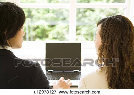 Stock Photo - Businessman and businesswoman using laptop computer. Fotosearch