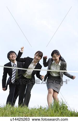 Stock Image - Businessman and businesswomen crossing finish line. Fotosearch