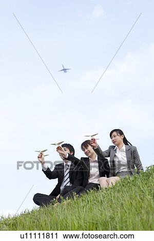 Stock Image - Businessman and businesswomen playing with paper planes. Fotosearch