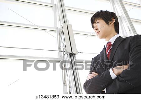 Businessman gazing out a window with arms crossed View Large Photo Image Stock Photo - Businessman gazing out a window with arms crossed. Fotosearch