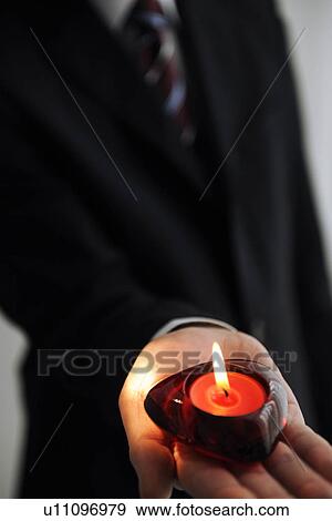Stock Photo - Businessman holding heart shaped candle. Fotosearch