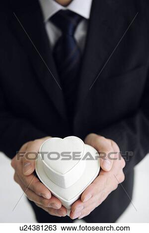 Stock Image - Businessman holding heart shaped gift boxes. Fotosearch