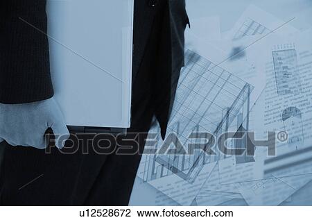 Stock Image - Businessman holding laptop and financial figures. Fotosearch