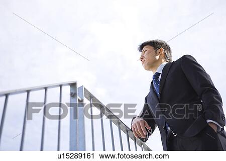 Businessman leaning on railing View Large Photo Image Stock Image - Businessman leaning on railing. Fotosearch