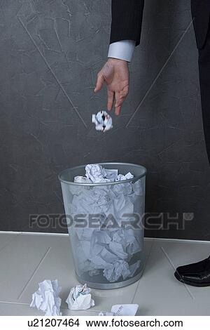 Picture - Businessman putting crumpled paper into wastepaper basket. Fotosearch