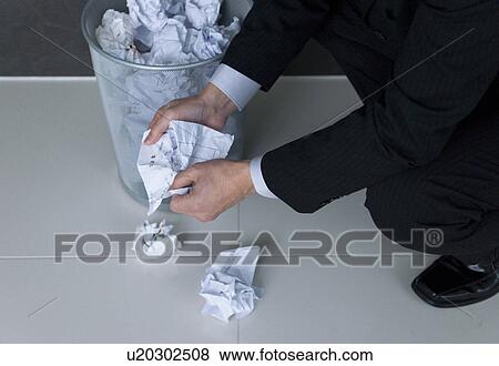 Stock Photo - Businessman putting crumpled paper into wastepaper basket. Fotosearch
