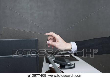 Businessman reaching for file on desk View Large Photo Image Stock Photo - Businessman reaching for file on desk. Fotosearch