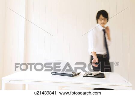 Stock Image - Businessman reaching for newspaper. Fotosearch