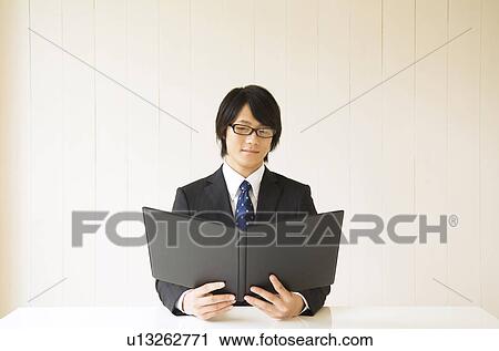 Businessman sitting at table reading file View Large Photo Image Stock Image - Businessman sitting at table reading file. Fotosearch
