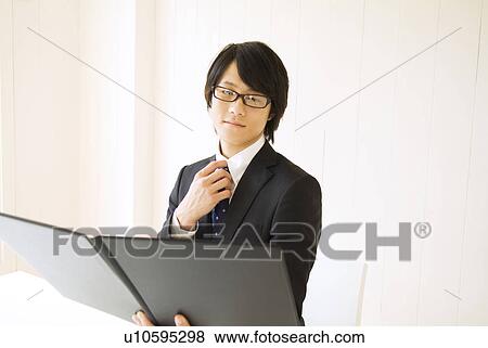 Businessman sitting at table reading file View Large Photo Image Stock Photo - Businessman sitting at table reading file. Fotosearch