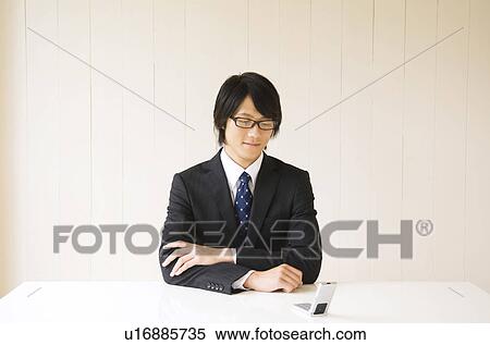 Stock Photography - Businessman sitting at table with mobile phone. Fotosearch