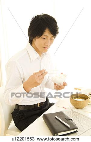 Stock Image - Businessman sitting eating breakfast. Fotosearch