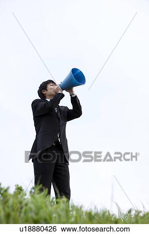 Businessman standing on grass with megaphone View Large Photo Image Stock Photograph - Businessman standing on grass with megaphone. Fotosearch