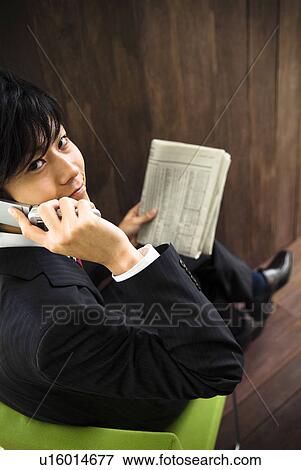 Businessman talking on a mobile phone while holding a newspaper View Large Photo Image Stock Photo - Businessman talking on a mobile phone while holding a newspaper. Fotosearch