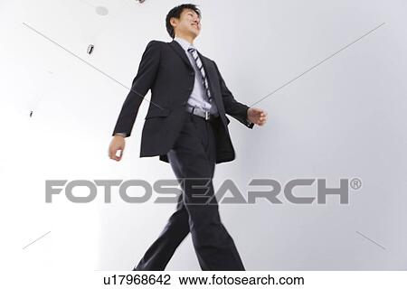 Stock Image - Businessman walking along a passage. Fotosearch