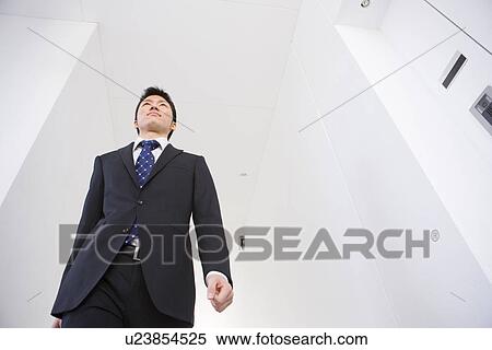 Stock Photography - Businessman walking along a passage. Fotosearch