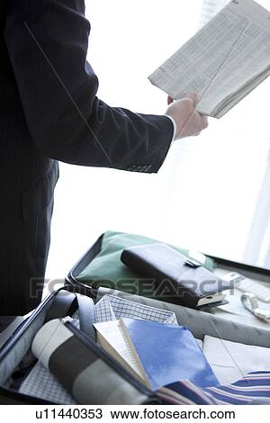 Businessman with a suitcase reading newspaper View Large Photo Image Stock Image - Businessman with a suitcase reading newspaper. Fotosearch
