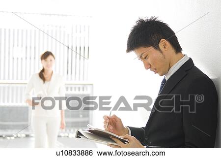 Stock Photograph - Businessman writing in personal organizer. Fotosearch