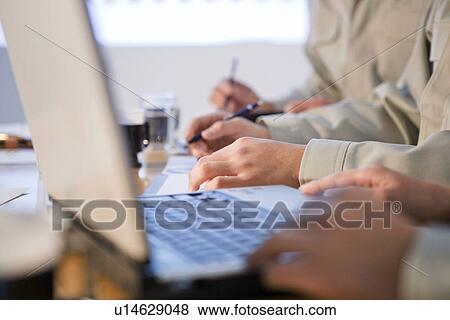 Businesspeople working on desk with laptop View Large Photo Image Stock Photo - Businesspeople working on desk with laptop. Fotosearch