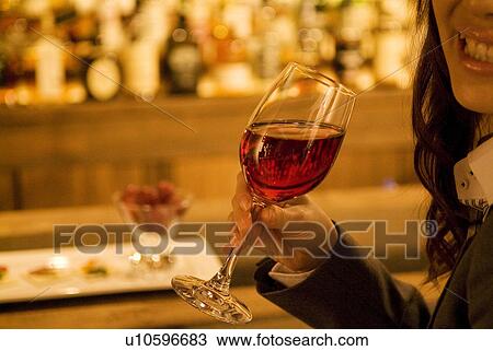 Stock Image - Businesswoman drinking wine at a bar. Fotosearch
