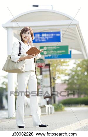 Businesswoman holding personal organizer at bus stop View Large Photo Image Stock Photo - Businesswoman holding personal organizer at bus stop. Fotosearch