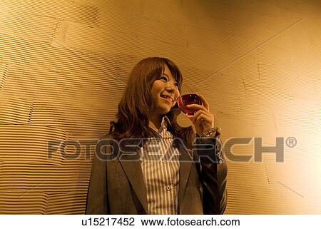 Businesswoman leaning against a wall with a glass of wine View Large Photo Image Stock Image - Businesswoman leaning against a wall with a glass of wine. Fotosearch