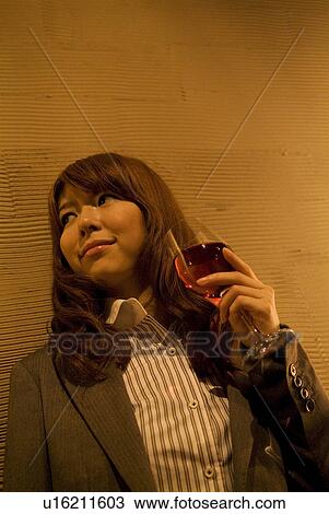 Businesswoman leaning against a wall with a glass of wine View Large Photo Image Stock Image - Businesswoman leaning against a wall with a glass of wine. Fotosearch