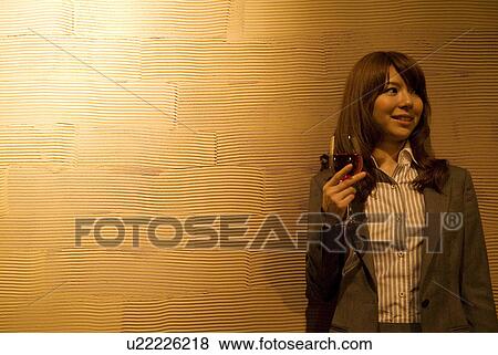 Businesswoman leaning against a wall with a glass of wine View Large Photo Image Stock Photo - Businesswoman leaning against a wall with a glass of wine. Fotosearch