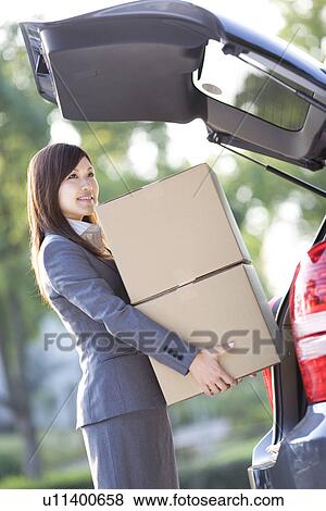 Stock Photo - Businesswoman loading cardboard boxes into car. Fotosearch
