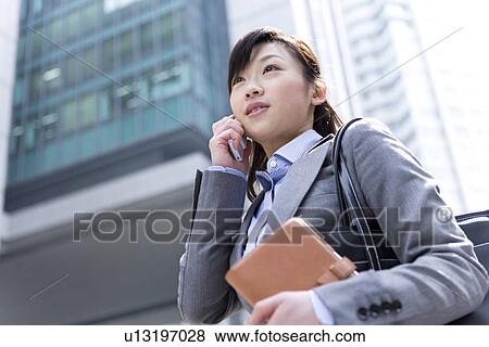 Stock Photo - Businesswoman on mobile phone with address book. Fotosearch