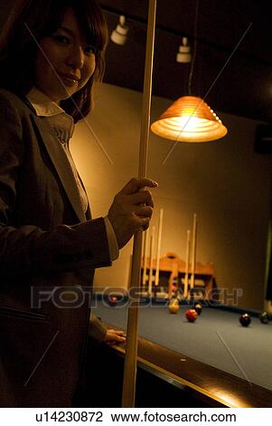 Stock Image - Businesswoman playing pool. Fotosearch