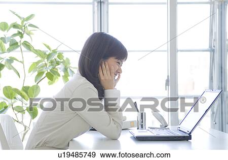 Stock Photo - Businesswoman smiling at laptop. Fotosearch