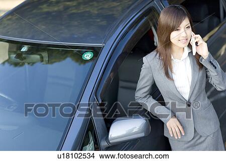 Businesswoman standing next to car talking on mobile phone View Large Photo Image Picture - Businesswoman standing next to car talking on mobile phone. Fotosearch