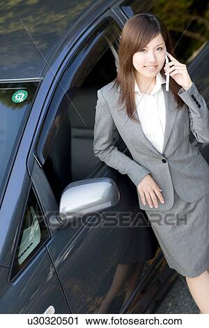 Businesswoman standing next to car talking on mobile phone View Large Photo Image Stock Image - Businesswoman standing next to car talking on mobile phone. Fotosearch