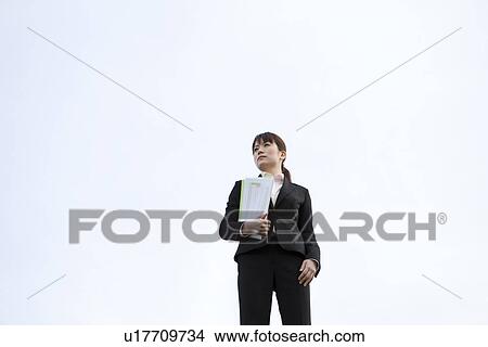 Picture - Businesswoman standing with file. Fotosearch