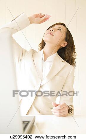 Stock Image - Businesswoman using eye drops. Fotosearch