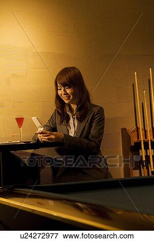 Stock Photo - Businesswoman using her phone at a bar. Fotosearch