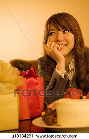 Stock Image - Businesswoman with gifts and a cake in front of her. Fotosearch