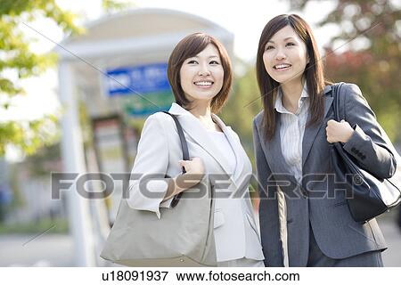Stock Photo - Businesswomen at bus stop. Fotosearch