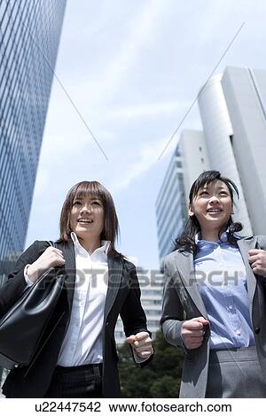 Stock Image - Businesswomen running in street. Fotosearch
